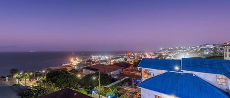 A coastal town at dusk with illuminated buildings and a view of the sea.