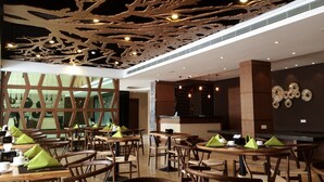 A modern restaurant interior with wooden furniture, a unique ceiling design, and a view through a large window. - Eska Hotel (Batam)