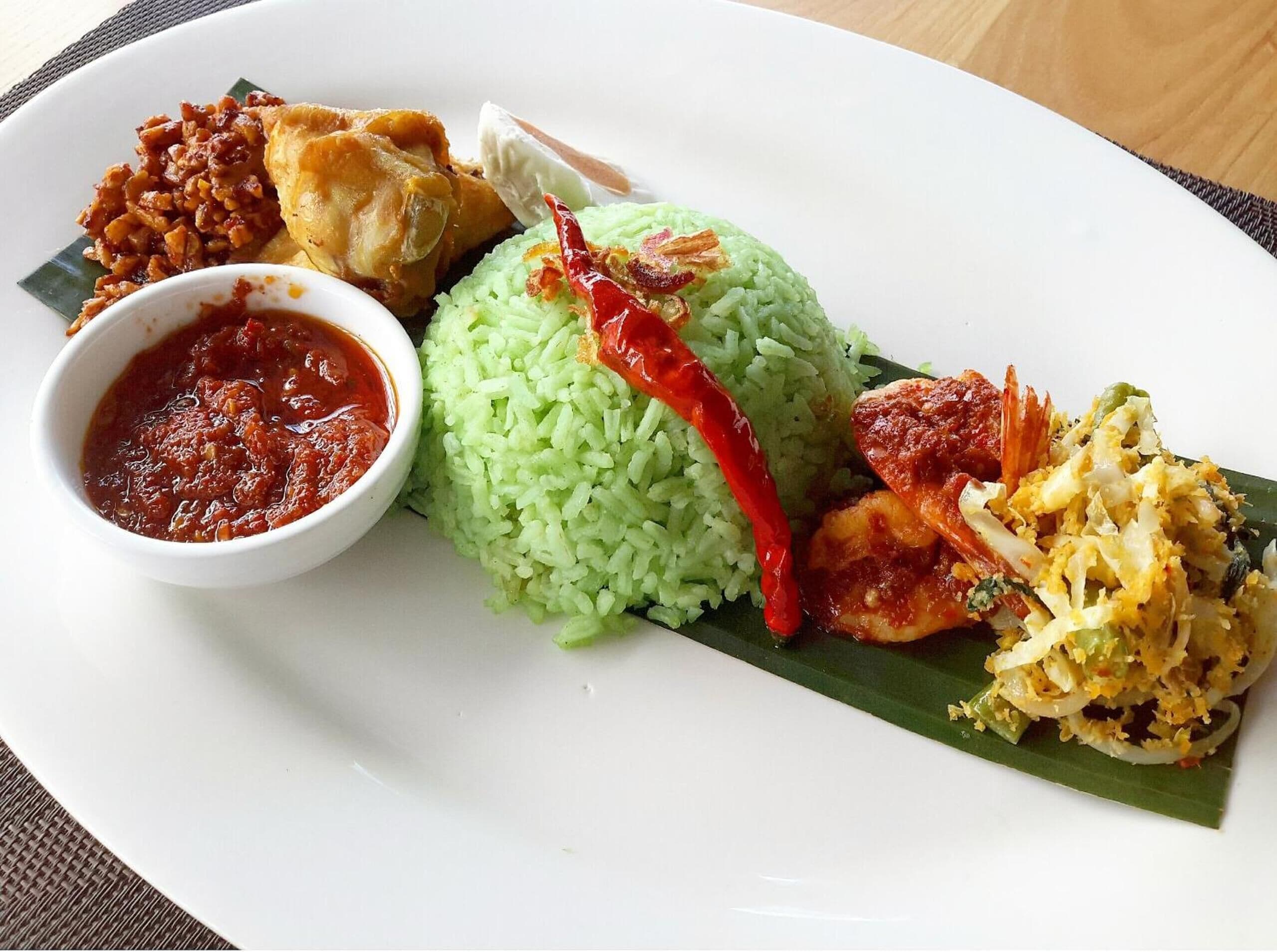 A plate of food with rice, a red chili, and various side dishes.