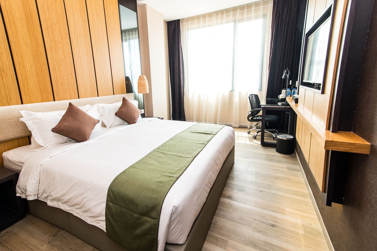 A hotel room with a large bed, a desk, and a chair.
