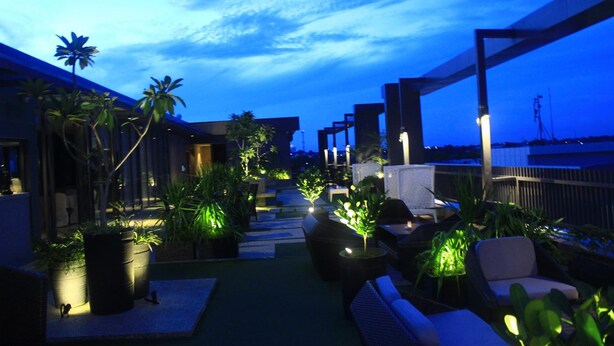 An outdoor seating area with potted plants and modern furniture, overlooking a body of water. - Eska Hotel (Batam)