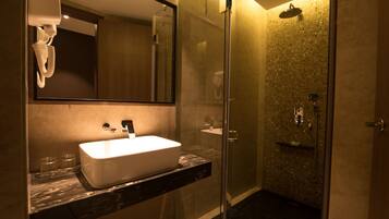 A modern bathroom with a large mirror, a white sink, and a glass-enclosed shower area.