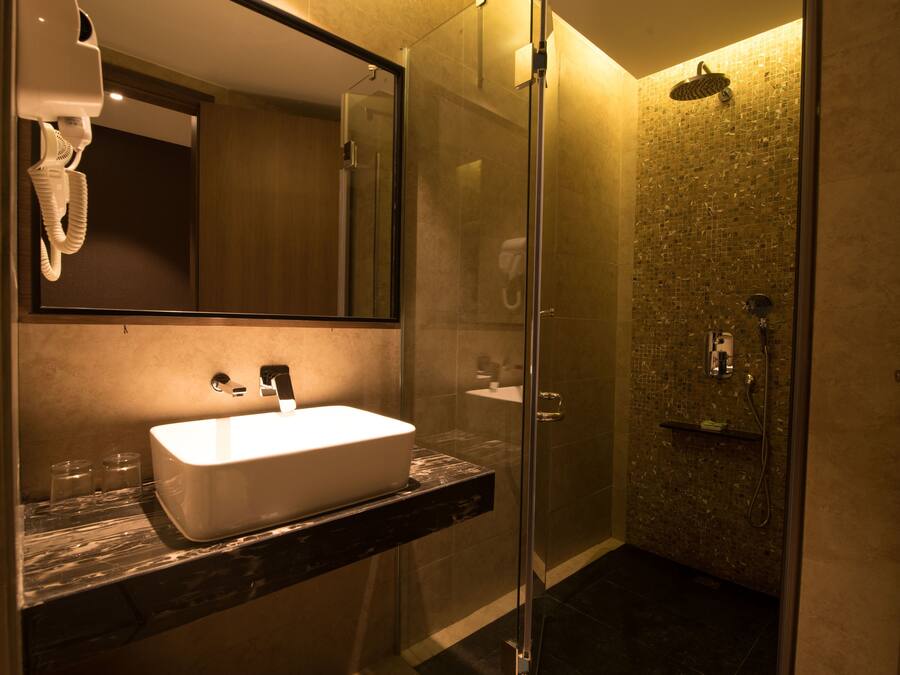 A modern bathroom with a large mirror, a white sink, and a glass-enclosed shower area.