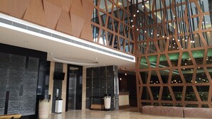 A modern lobby with a high ceiling, geometric wooden paneling, and a reception desk. - Eska Hotel (Batam)