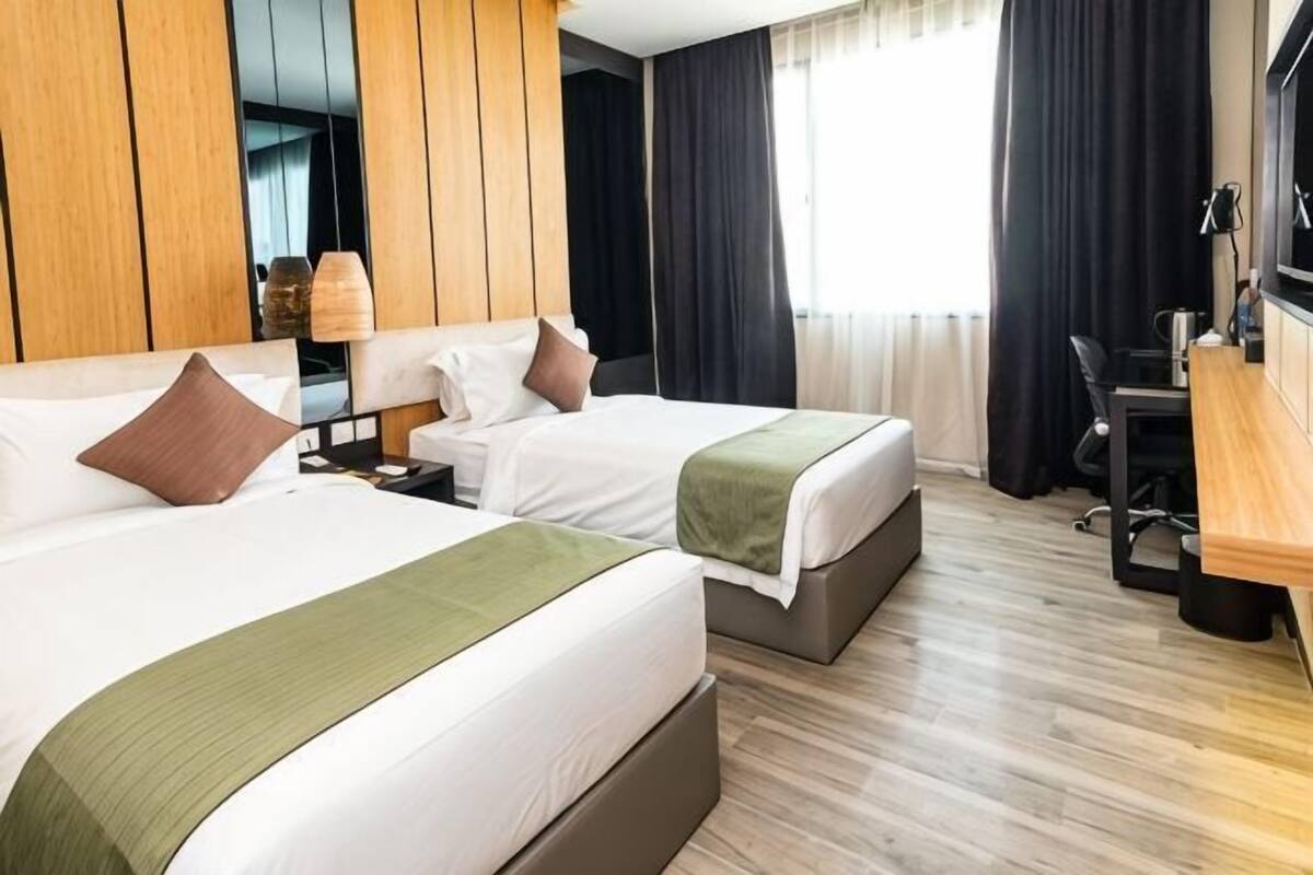 A hotel room with two beds, a desk, a chair, and a TV.