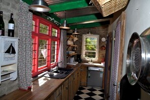 Una cocina compacta con una puerta roja, un refrigerador pequeño y un lavamanos.