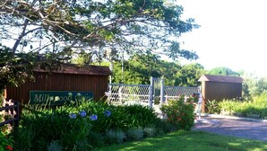 A gated property with a wooden fence, a sign reading "Milkmood Clinic," and a building with a red roof.