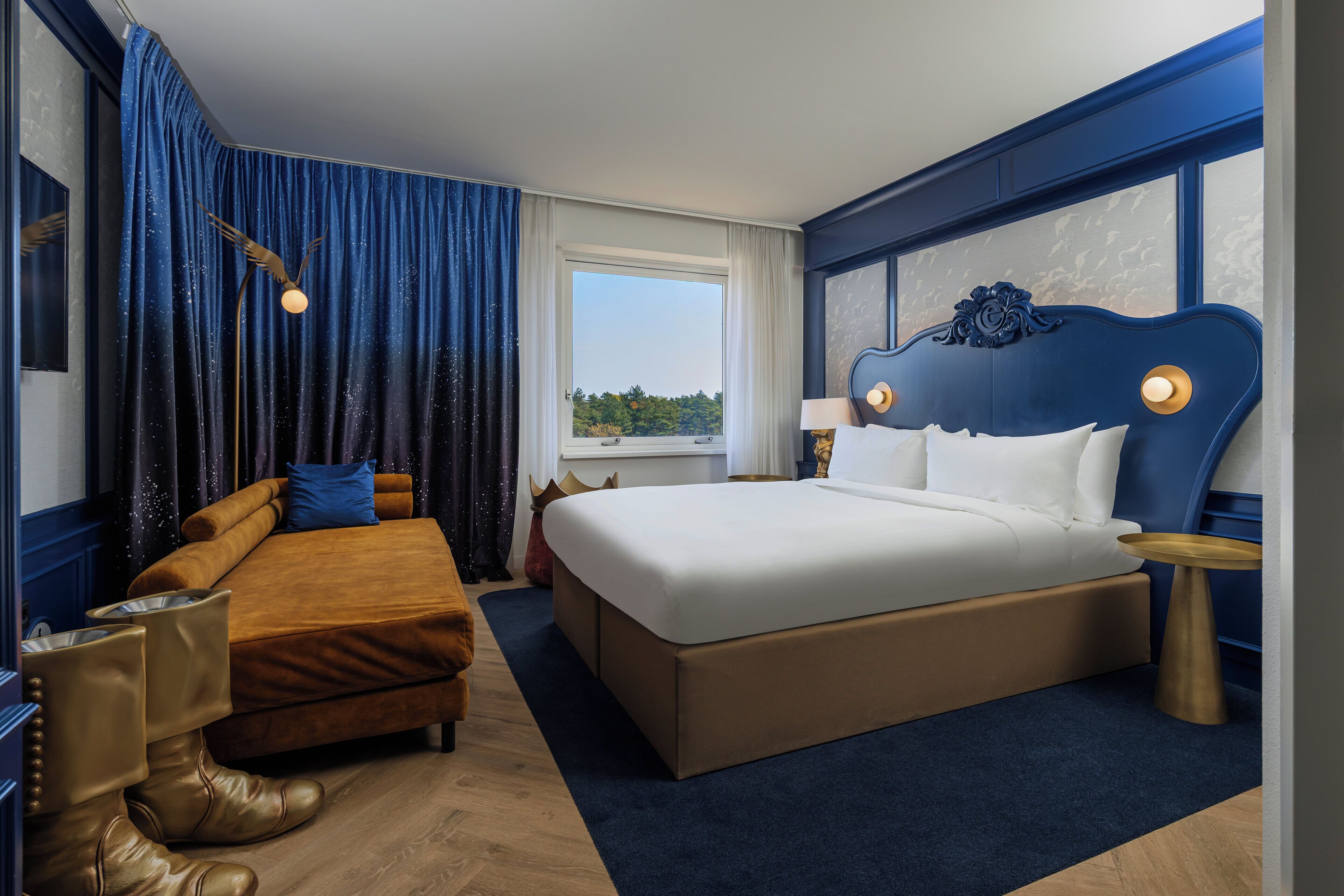 Ein Hotelzimmer mit einem großen Bett, einem Schlafsofa, einem Beistelltisch und einem Fenster mit Blick.