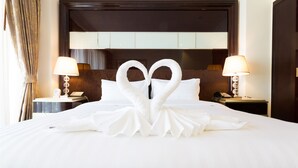 Habitació d'hotel amb un llit, dues mesetes de nit, làmpades i un cigne decoratiu fet amb tovalloles.
