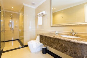 Une salle de bain moderne avec une douche à parois de verre, un lavabo en marbre et un grand miroir.