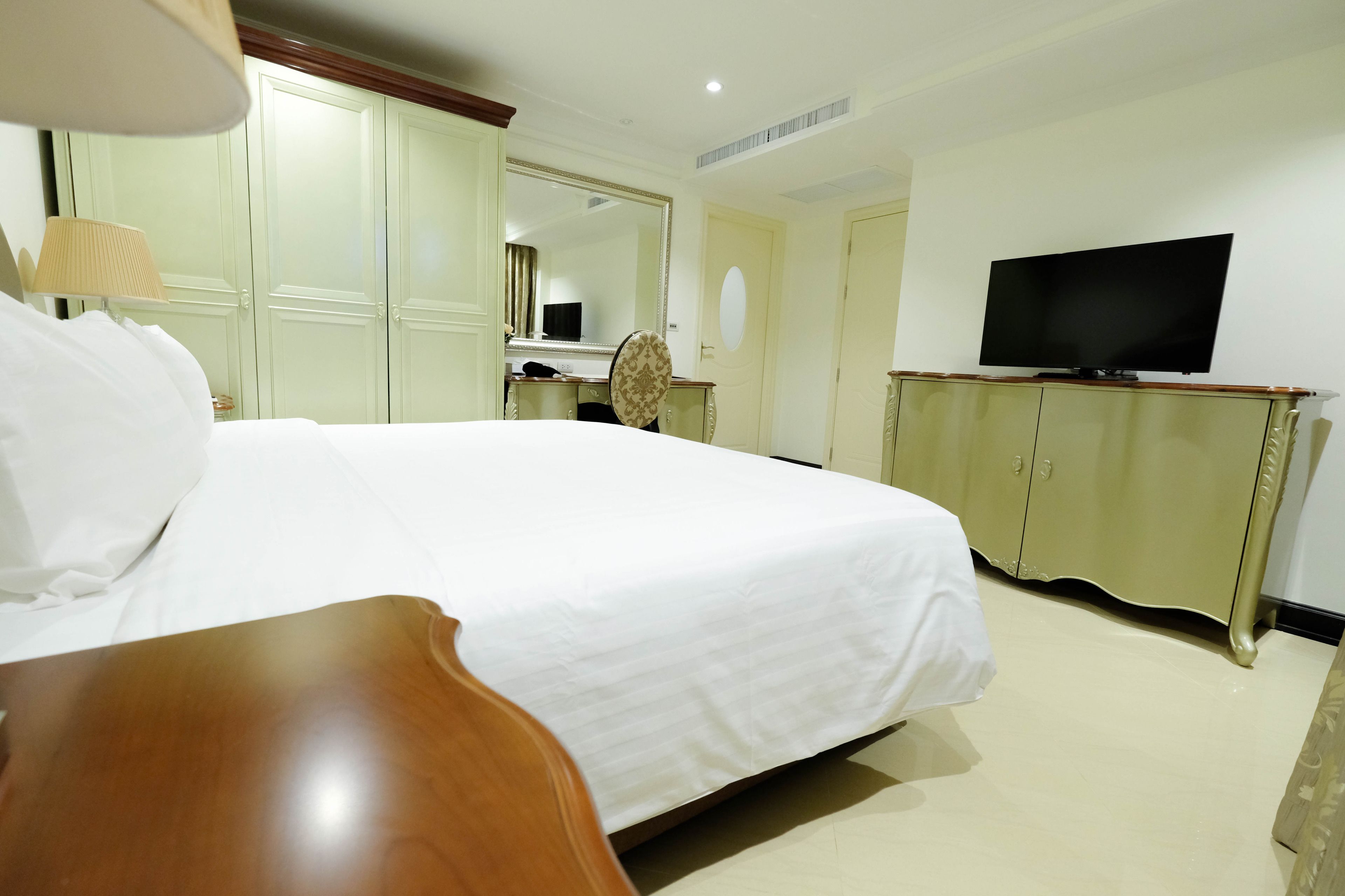 A hotel room with a large bed, a television, a wardrobe, and a desk.