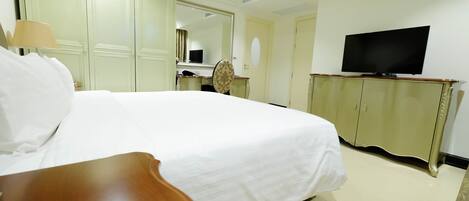 A hotel room with a large bed, a television, a wardrobe, and a desk.