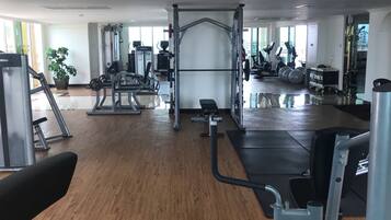Un gimnasio con diversos equipos de ejercicio, incluyendo una estructura para sentadillas, bancos y máquinas de cardio.