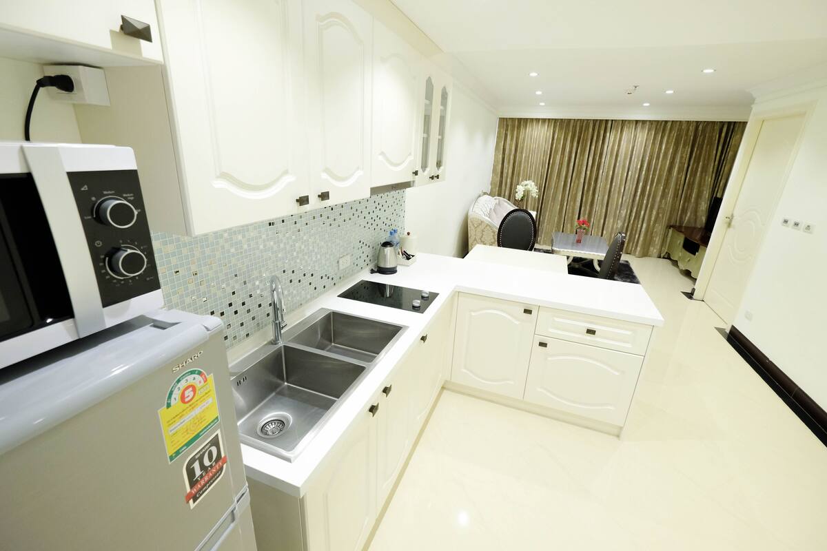 A modern kitchen with white cabinets, a double sink, and a built-in oven.