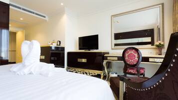 A hotel room with a large bed, a flat-screen TV, a desk with a computer, a chair, and a mirror.