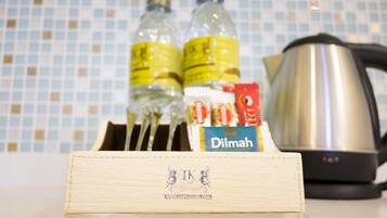 A kitchen counter with a coffee maker, two bottles of water, a box of tea, and a wooden box with a logo.