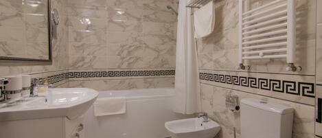 Un baño con bañera, inodoro, bidé y lavamanos.