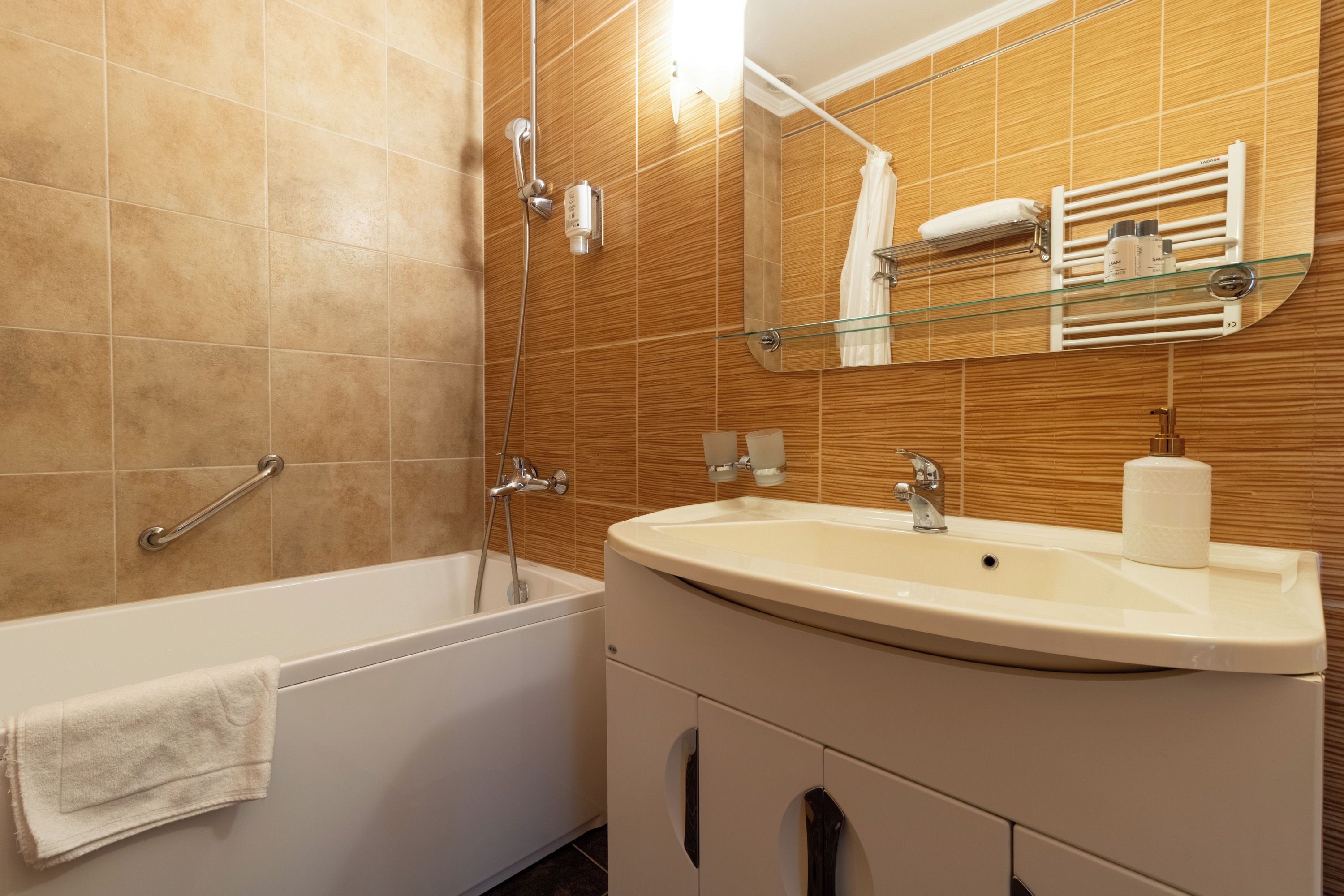 A bathroom with a bathtub, a sink, and a mirror.