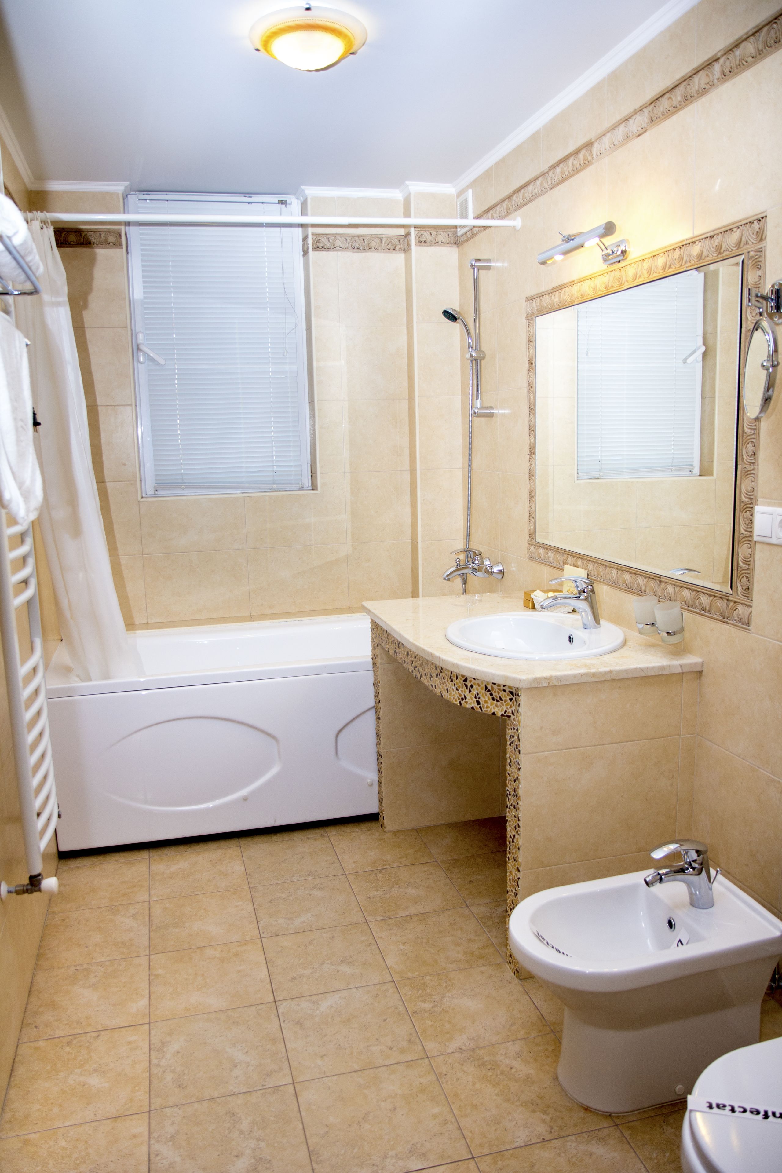 Une salle de bain équipée d’une baignoire, d’un lavabo, d’un bidet et d’un miroir.