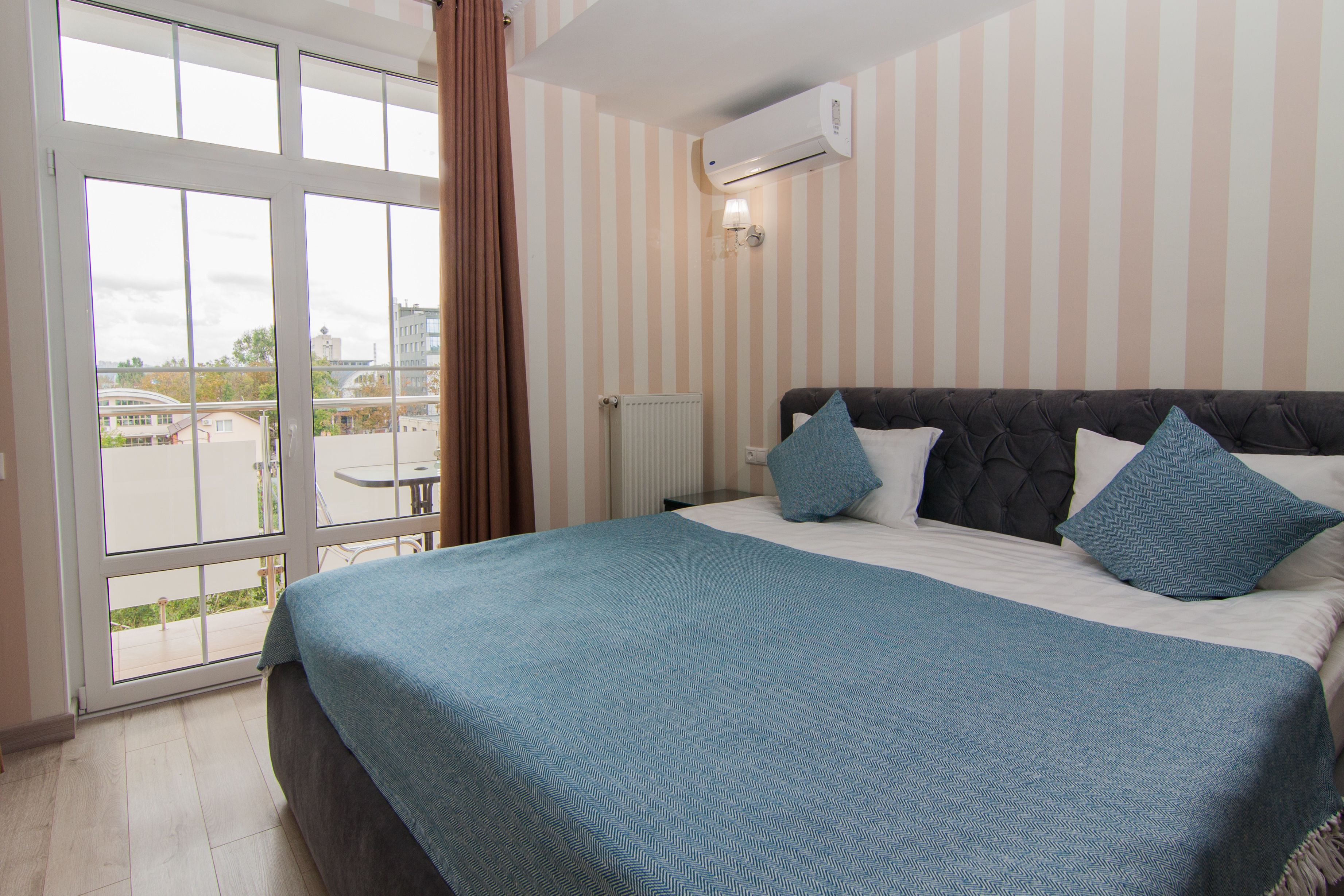 Habitación de hotel con una cama grande, paredes a rayas y vistas a través de un ventanal.