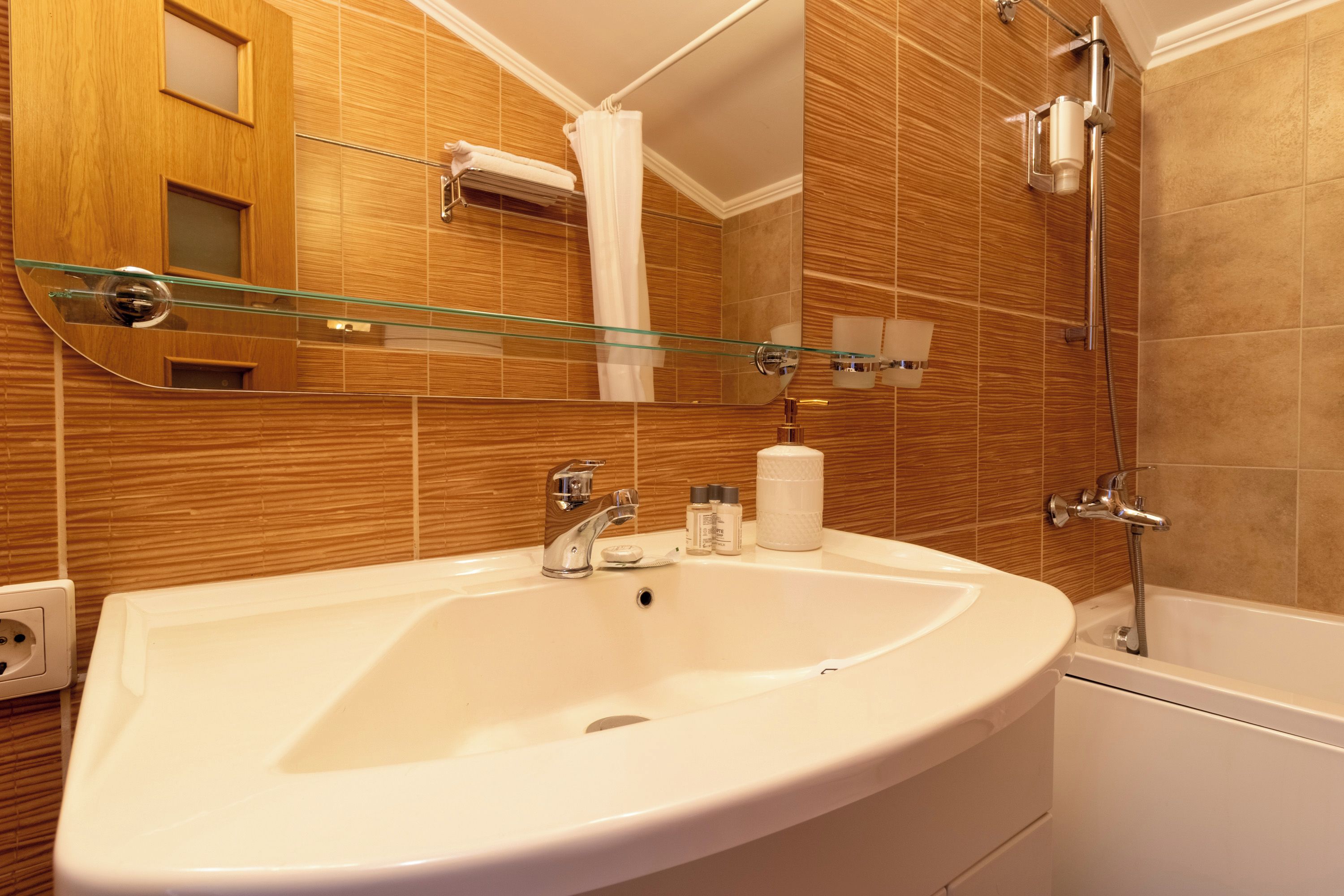 A bathroom with a white sink, a glass shower enclosure, and wooden paneling on the walls.