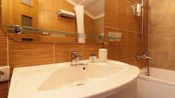 A bathroom with a white sink, a glass shower enclosure, and wooden paneling on the walls.