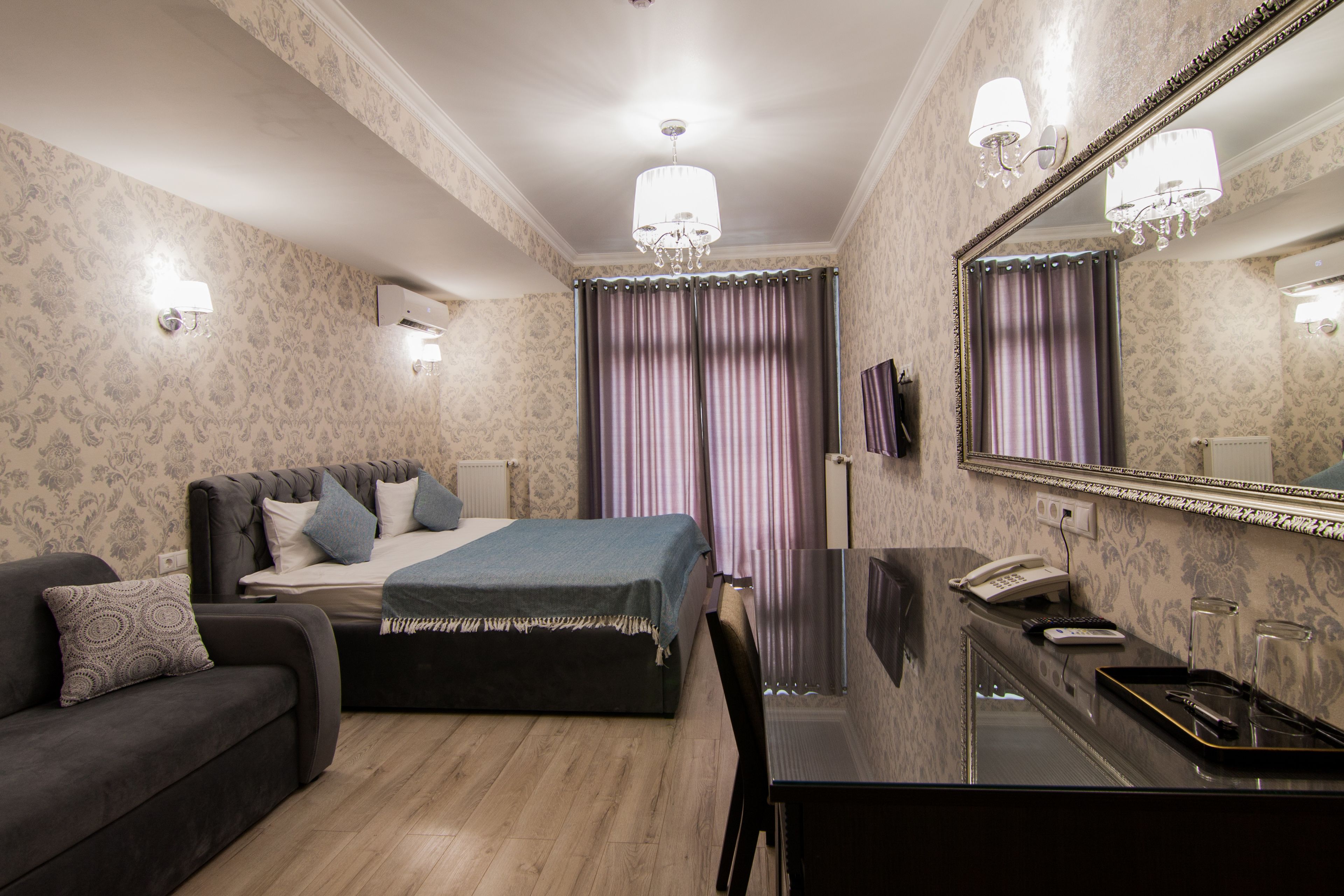 Un dormitorio con cama, sofá, escritorio y espejo.