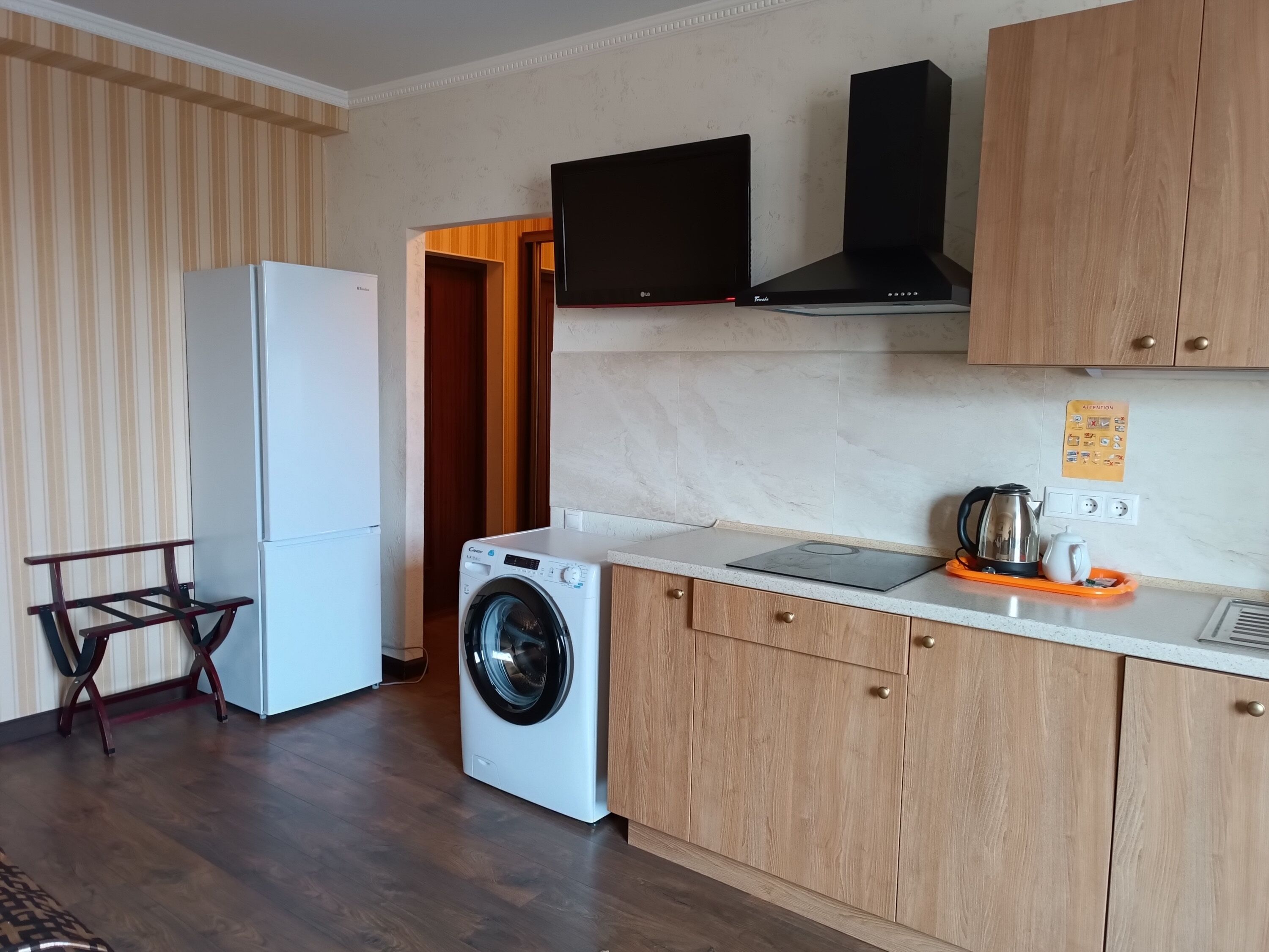 A compact kitchen with a washing machine, a refrigerator, a microwave, and a coffee maker.