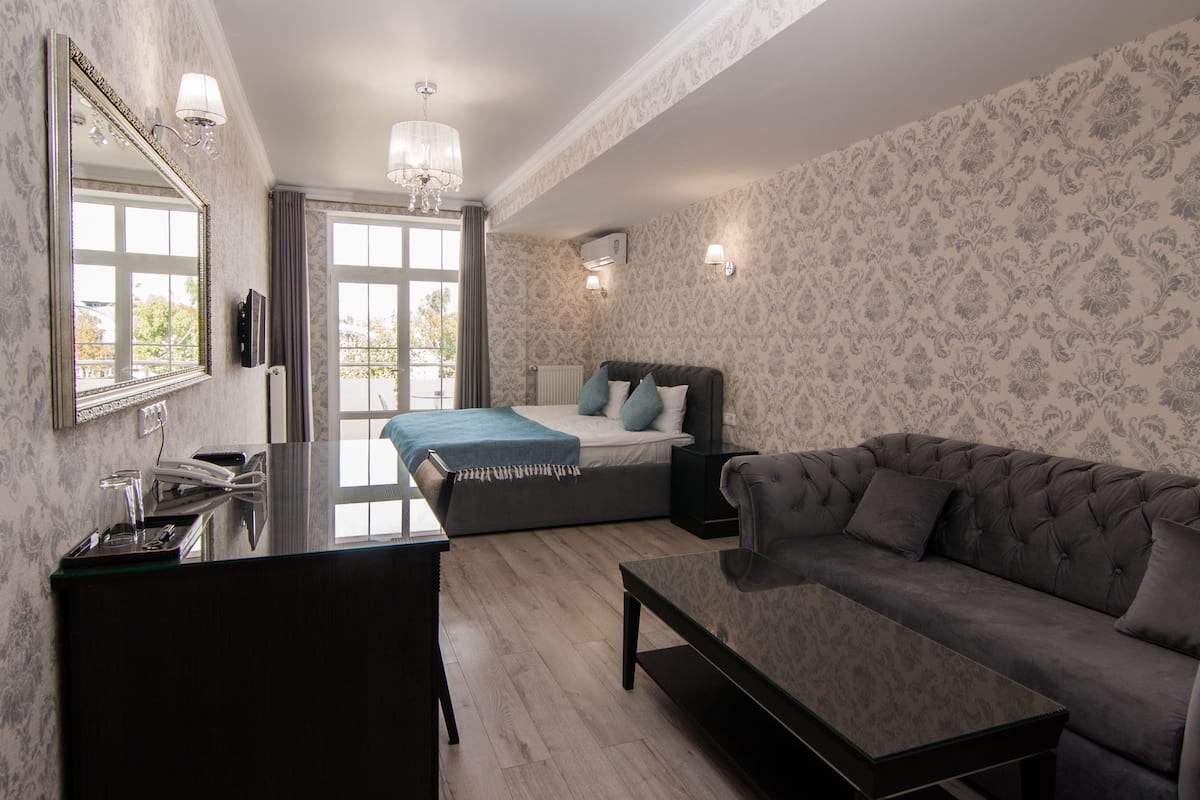 Une chambre moderne avec un lit, un canapé, un bureau et un grand miroir.