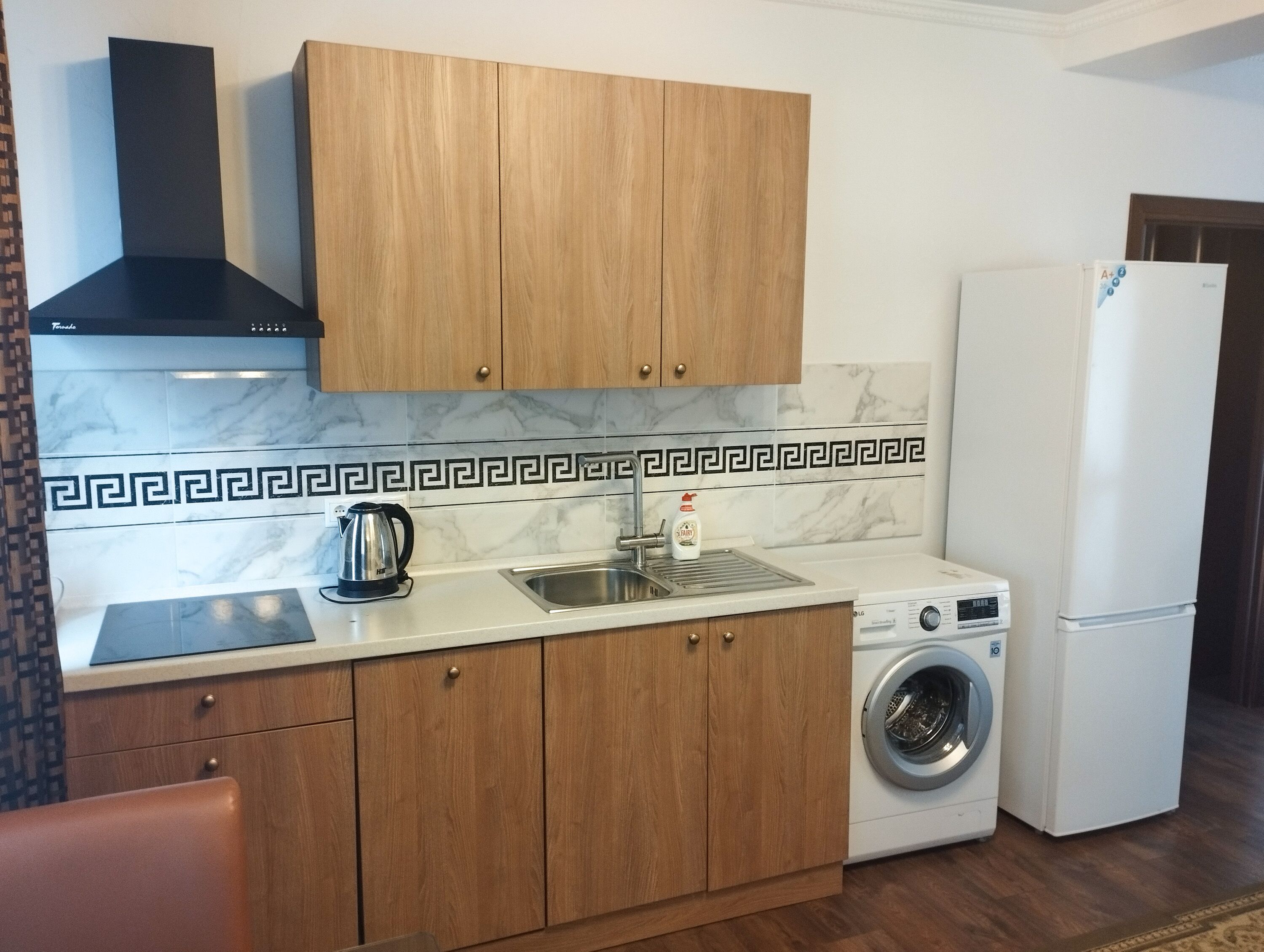 Una cocina compacta con armarios de madera, estufa integrada, lavamanos y lavadora.