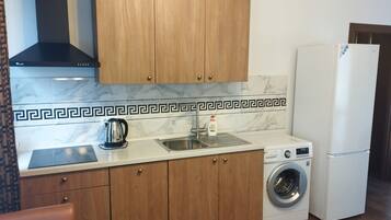 Una cocina compacta con armarios de madera, estufa integrada, lavamanos y lavadora.