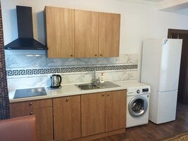 Una cocina compacta con armarios de madera, estufa integrada, lavamanos y lavadora.