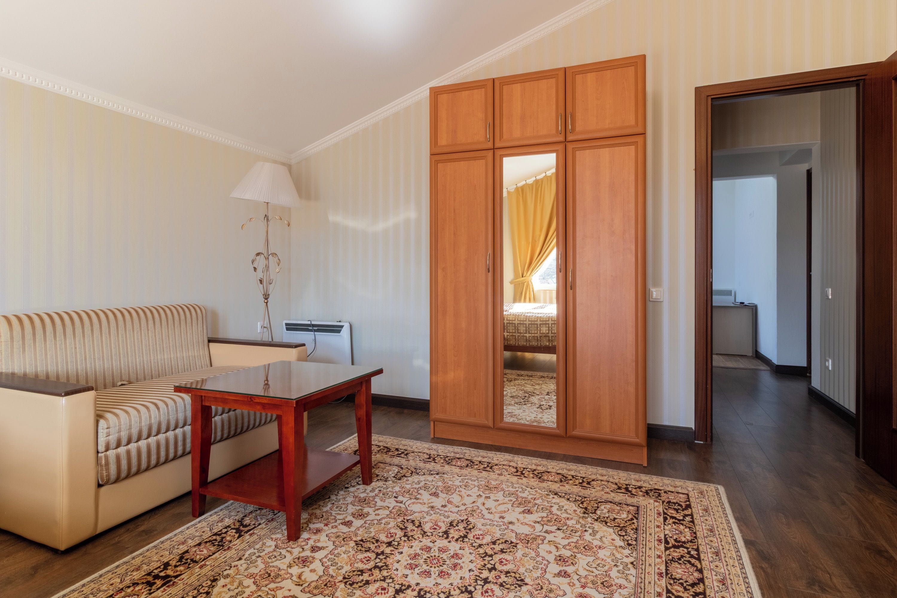 Un salon avec un canapé, une table, un miroir et un tapis à motifs.
