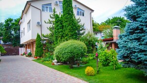 A two-story house with a paved driveway, surrounded by well-maintained gardens and trees. - Klassik Hotel (Chisinau)