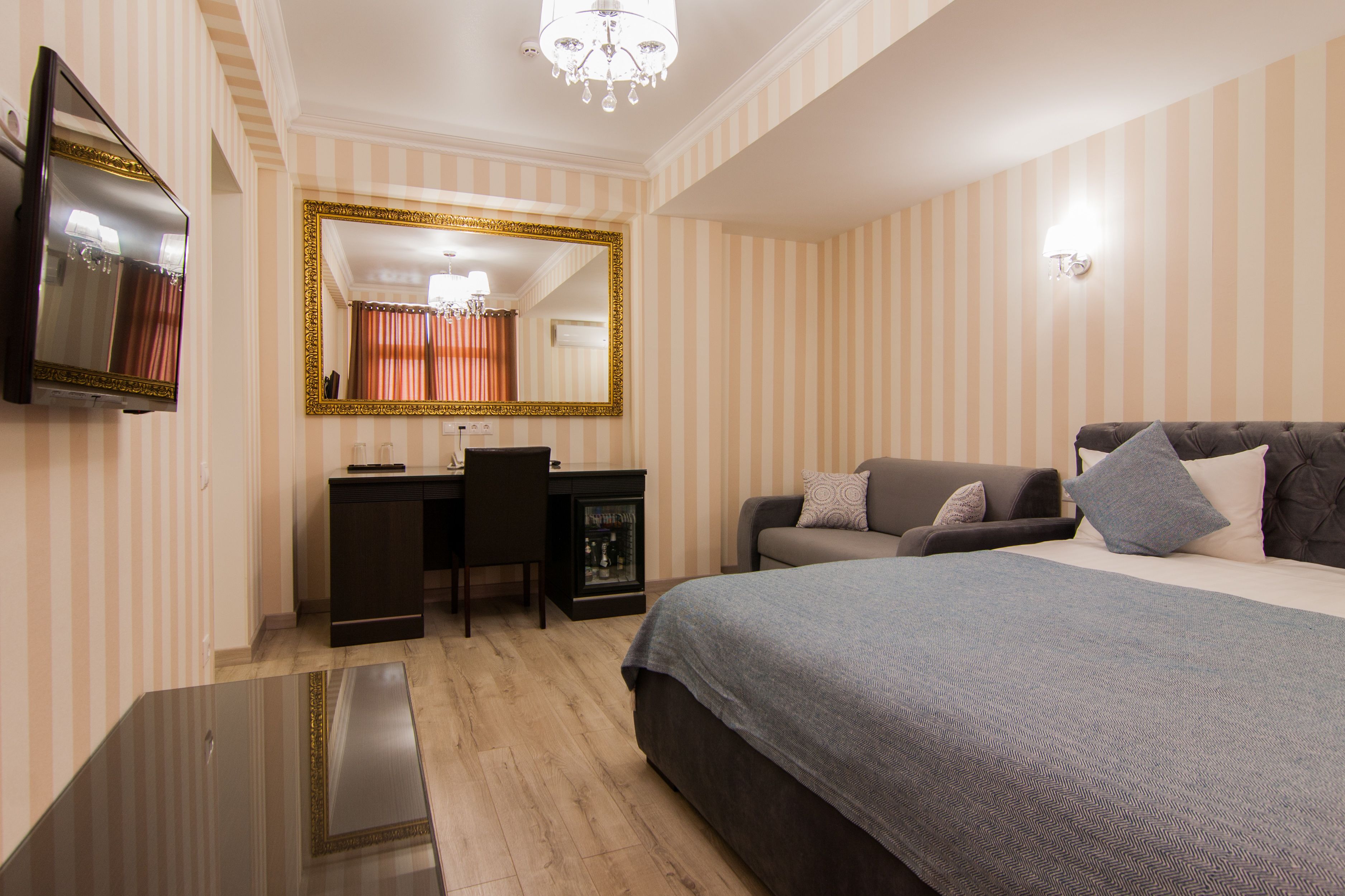 Une chambre d’hôtel avec un grand lit, un bureau avec une chaise, une télévision et un miroir.