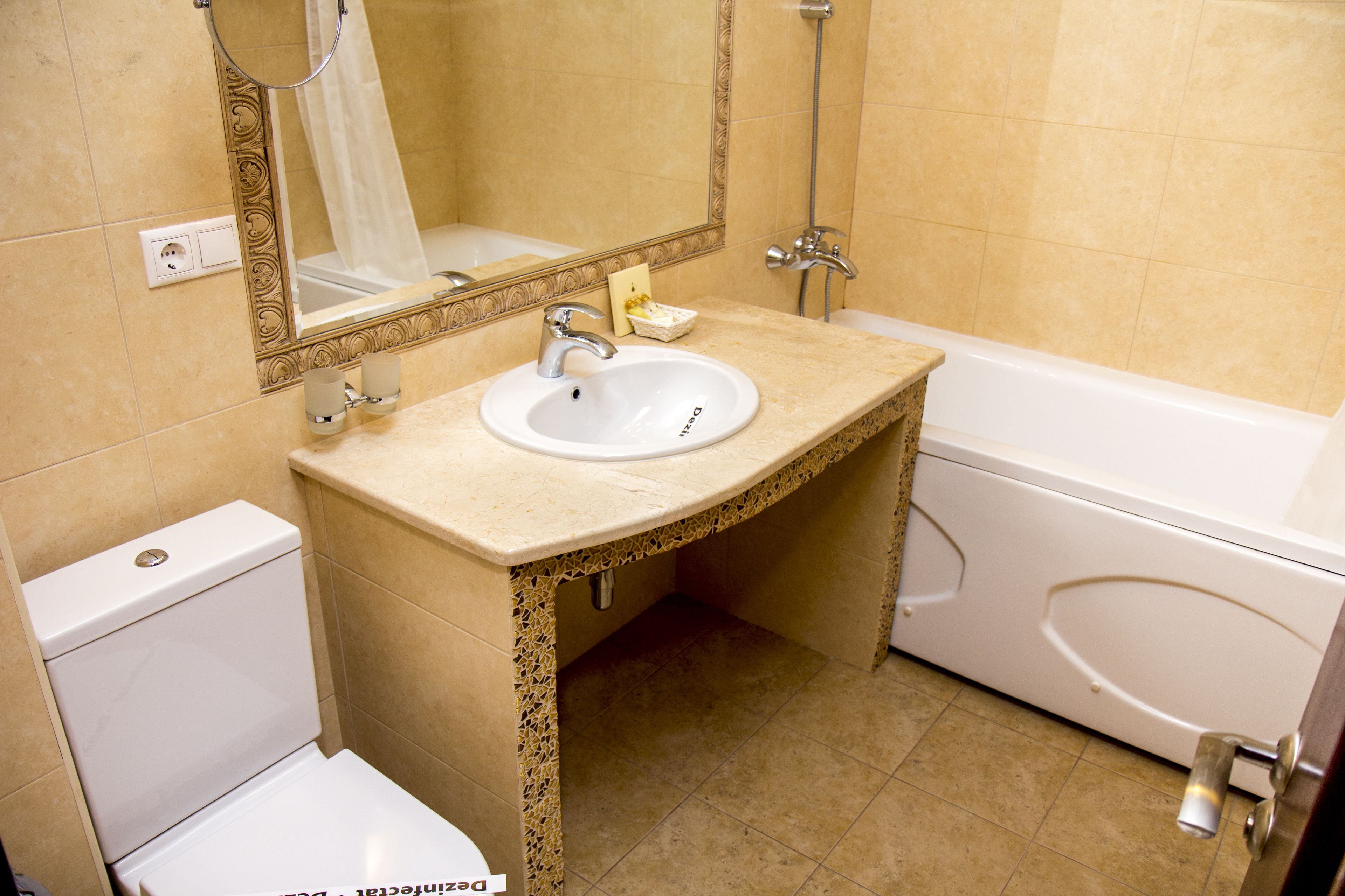 Un baño con lavamanos, espejo, inodoro y bañera.