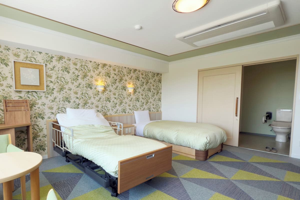 Una habitación de hotel con cama, mesita de noche, silla y una pequeña mesa.
