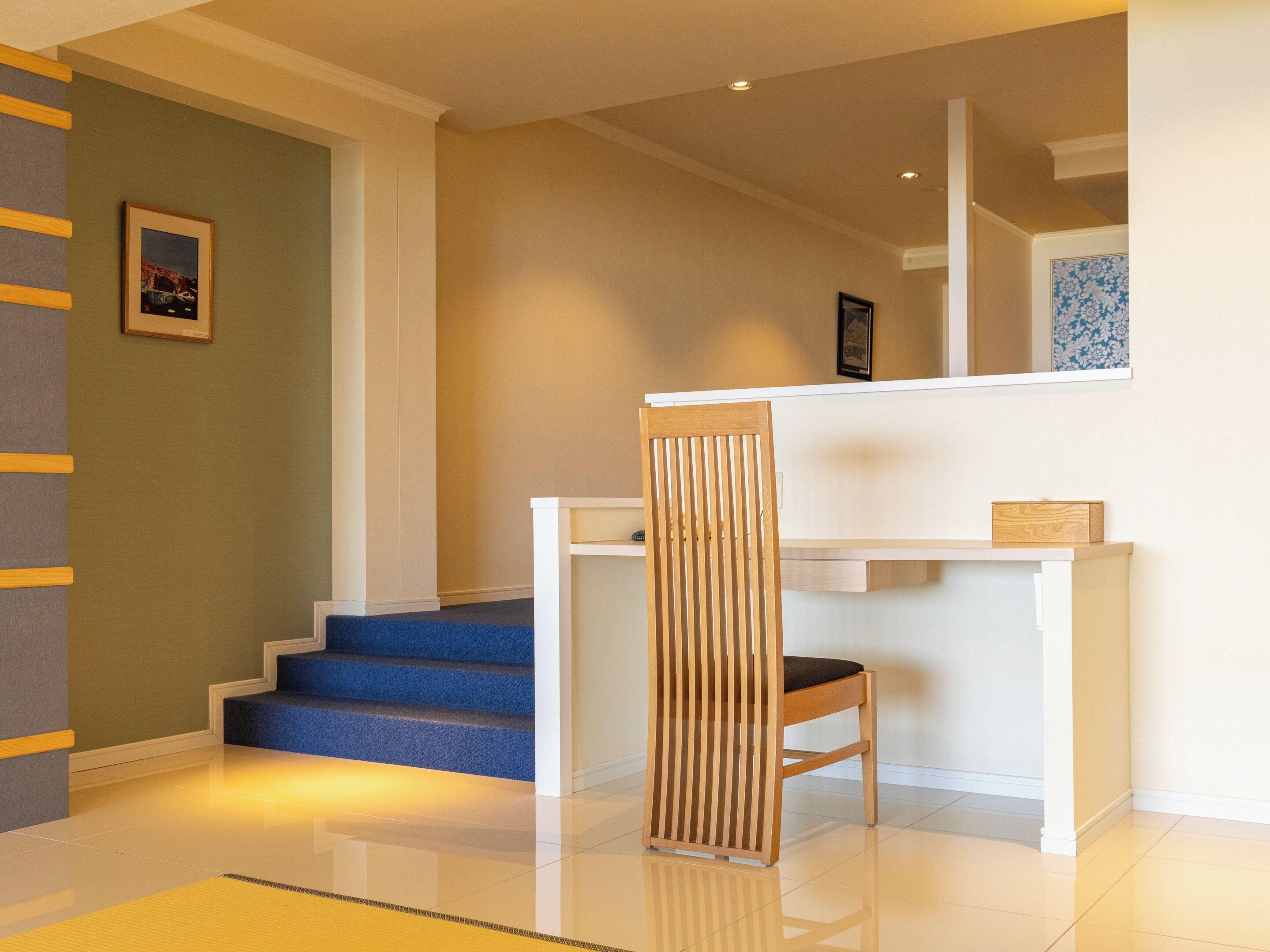 Ein modernes Interieur mit einer Treppe, die zu einer zweiten Etage führt, einem Holzstuhl und einem weißen Konsolentisch.