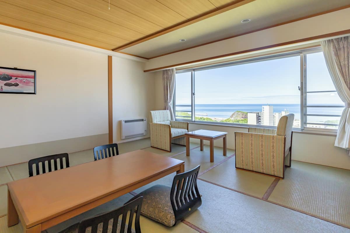Una habitación con techo de madera, un ventanal con vista al mar, una mesa, sillas y un sofá.