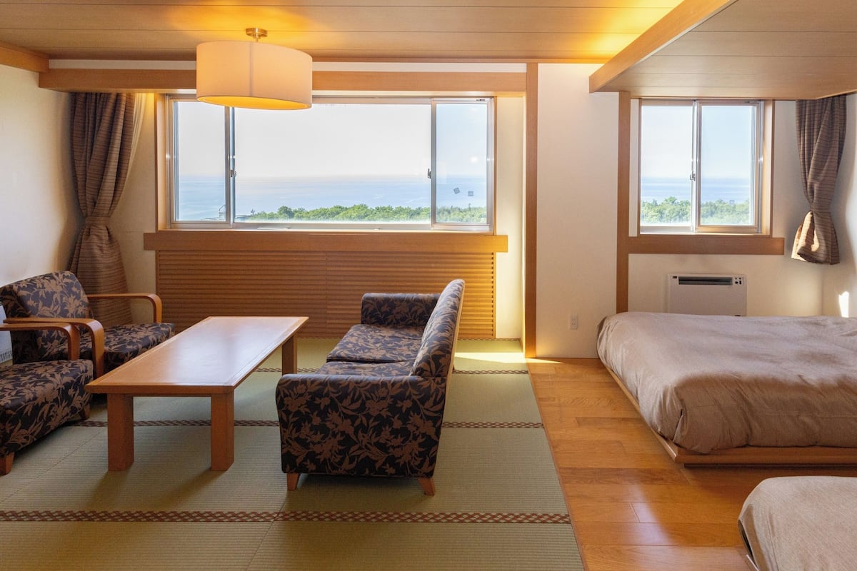 Habitación de hotel con sofá, mesa, cama y vista al mar.