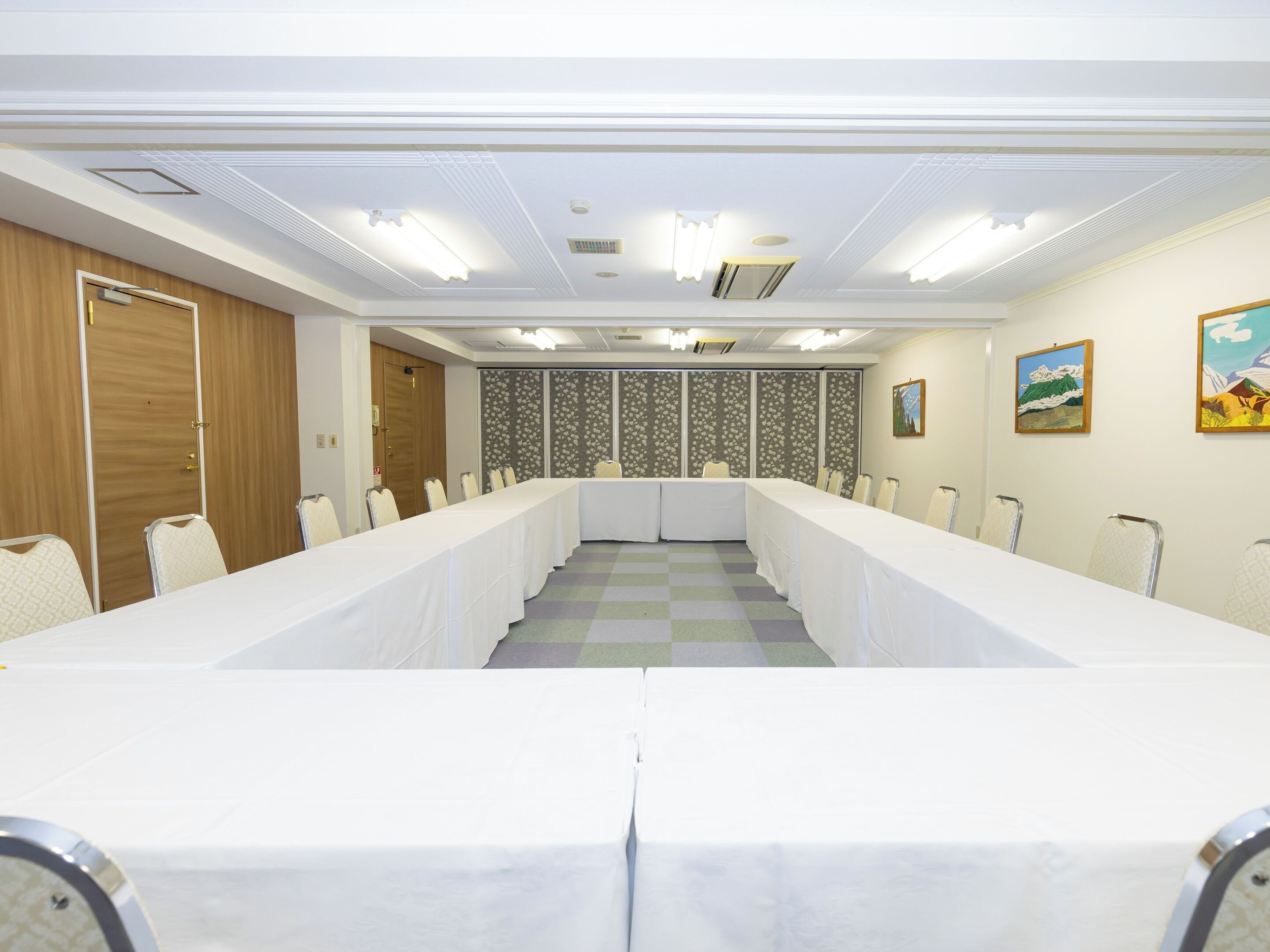 A conference room with a long table, chairs, a wooden door, and a patterned wall.