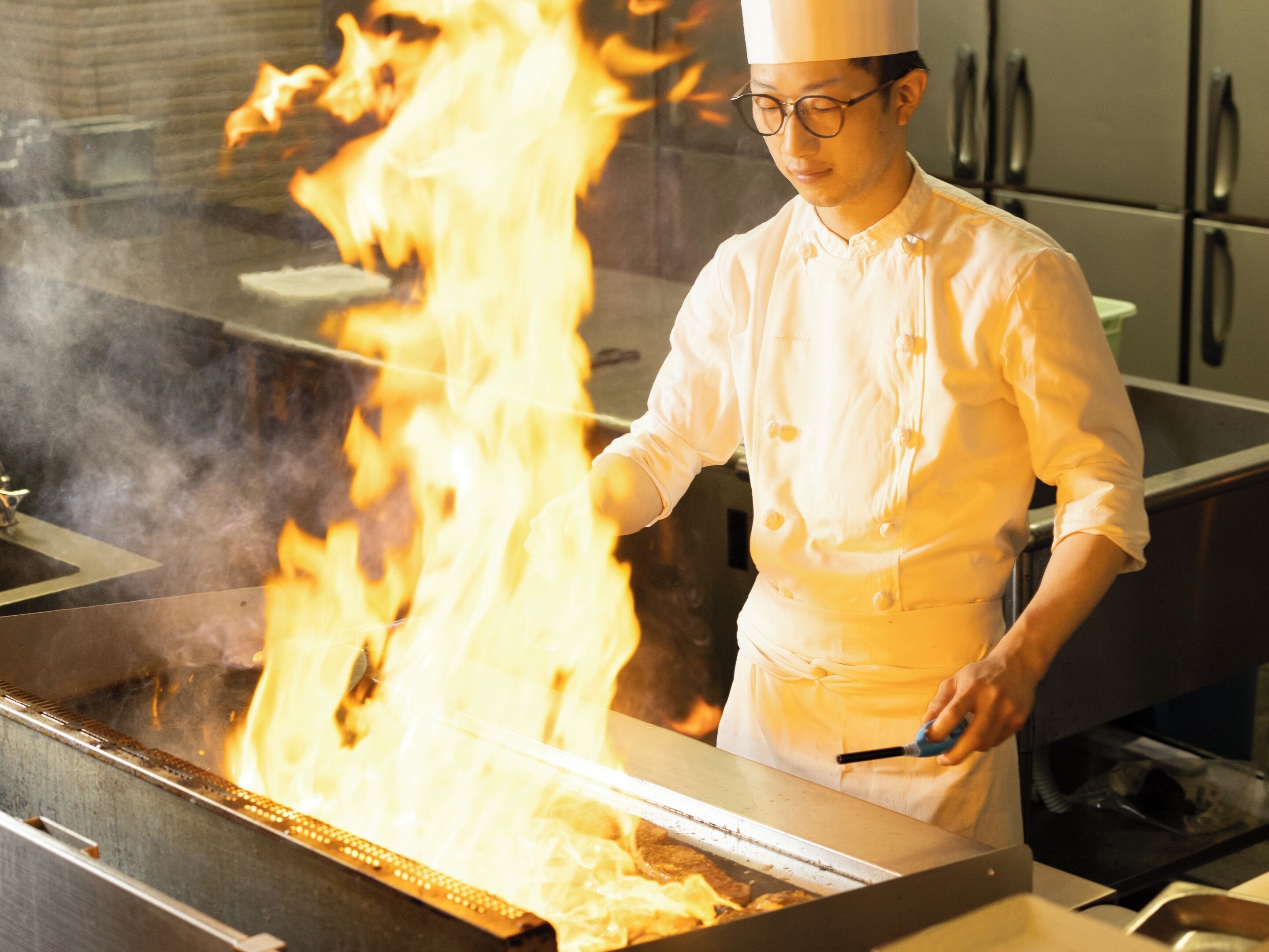 Un chef cocina con llamas en una cocina.