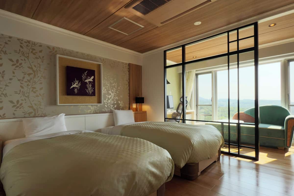 Habitación de hotel con dos camas, un ventanal con vistas y techo de madera.
