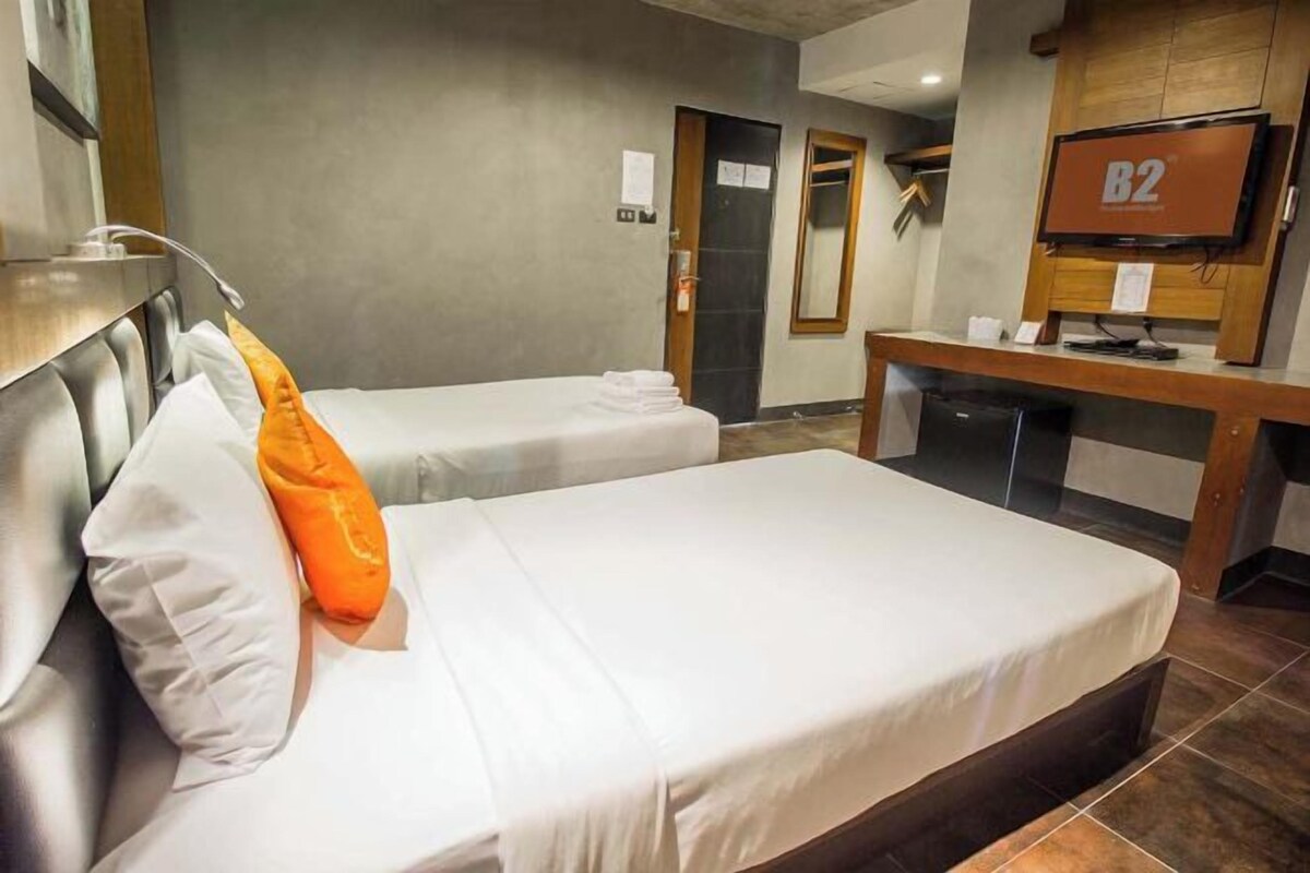 Ein Hotelzimmer mit zwei Betten, einem Schreibtisch und einem Fernseher.