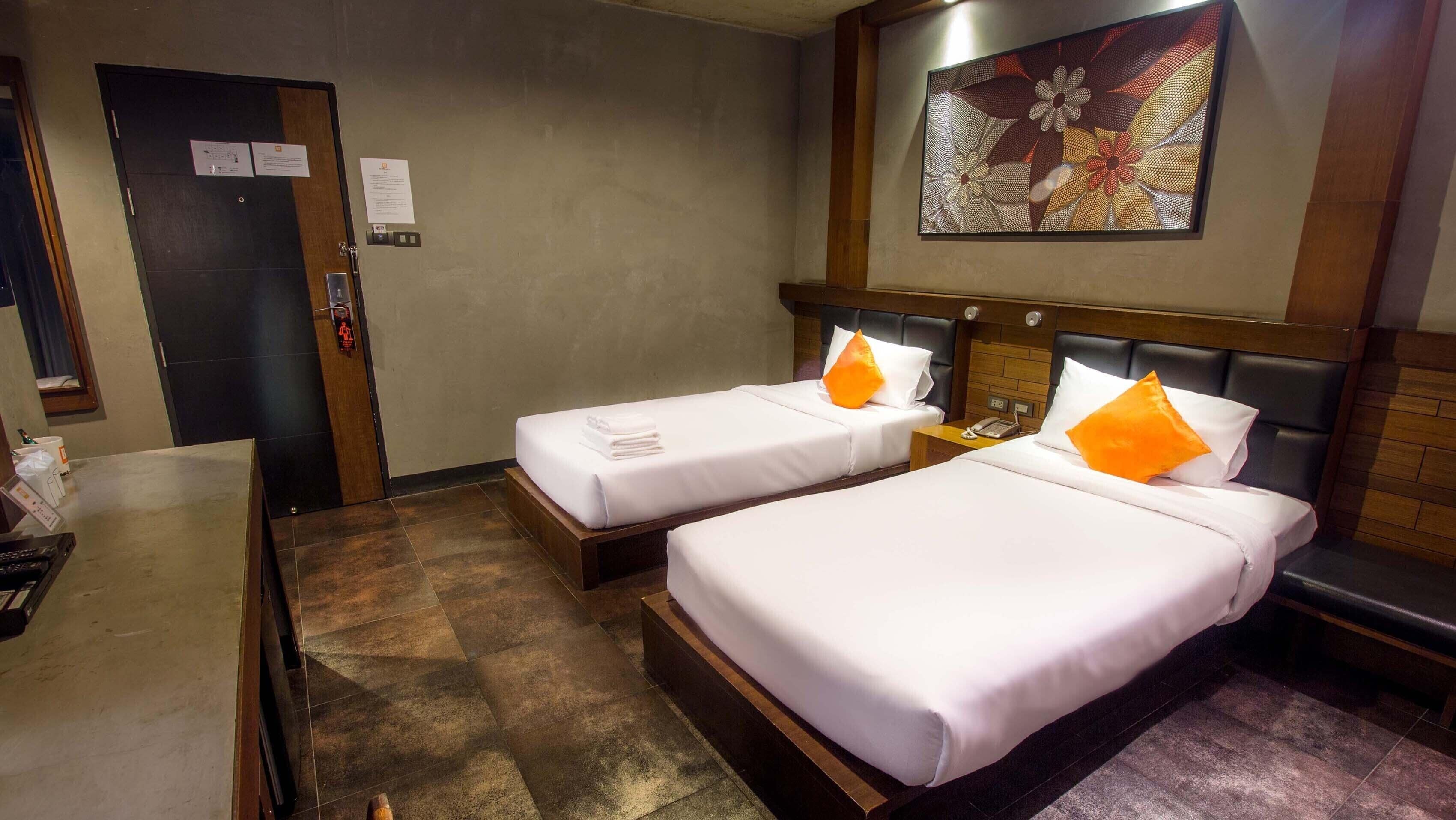 Una habitación de hotel con dos camas, un escritorio y un cuadro en la pared.
