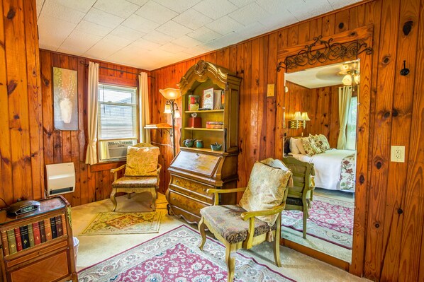 Una habitación acogedora con paredes de madera, un piano antiguo, una cama y un espejo que refleja el ambiente.