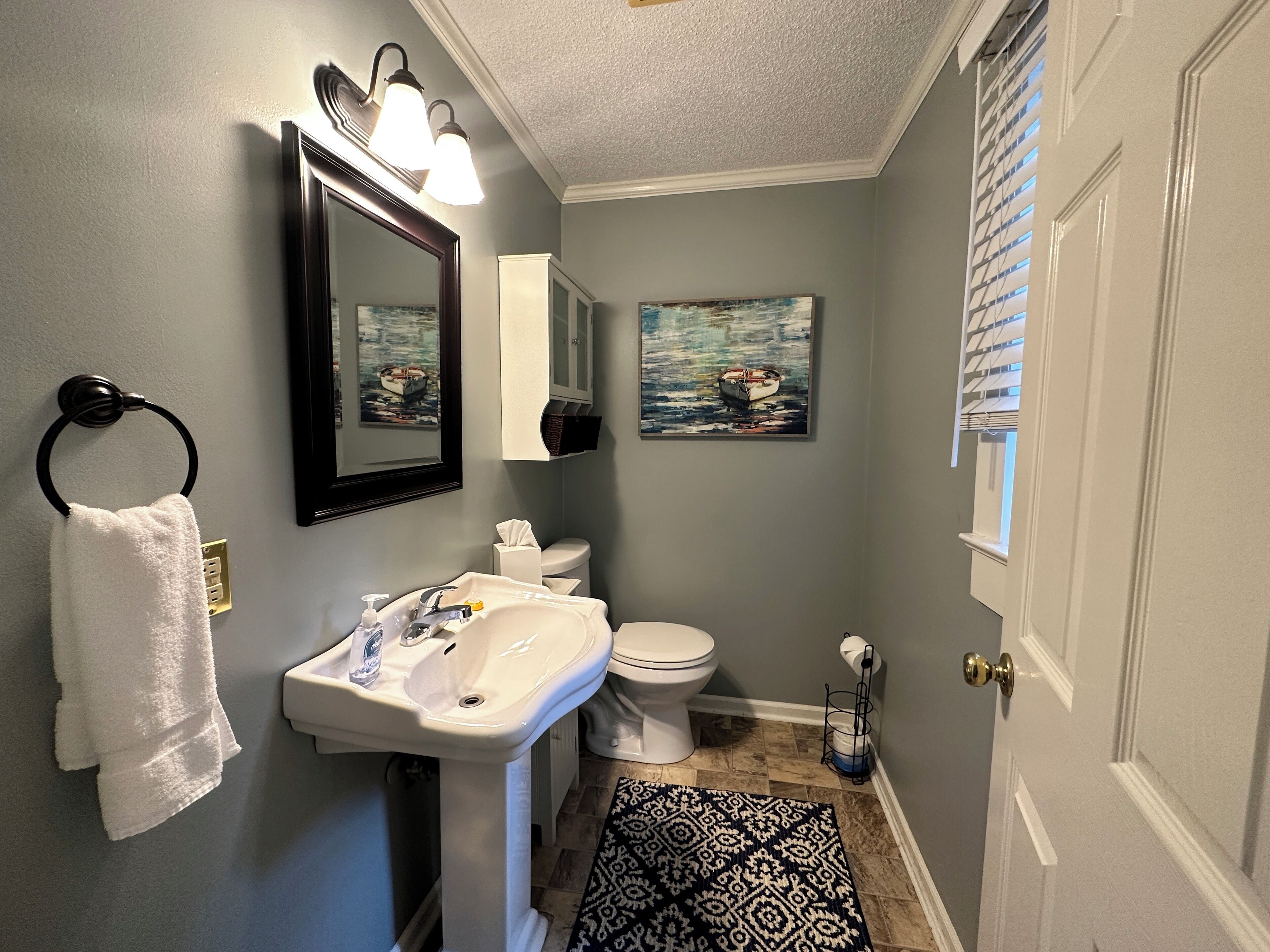 A bathroom with a sink, toilet, and two framed paintings on the wall.