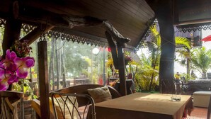An indoor dining area with a wooden table, chairs, and a view of the outdoors. - Phangan Cove (Ko Pha-ngan)