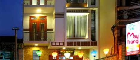 Un hôtel à plusieurs étages, doté d’une entrée bien éclairée, d’un espace extérieur aménagé pour s’asseoir et d’une enseigne de restaurant bien visible.