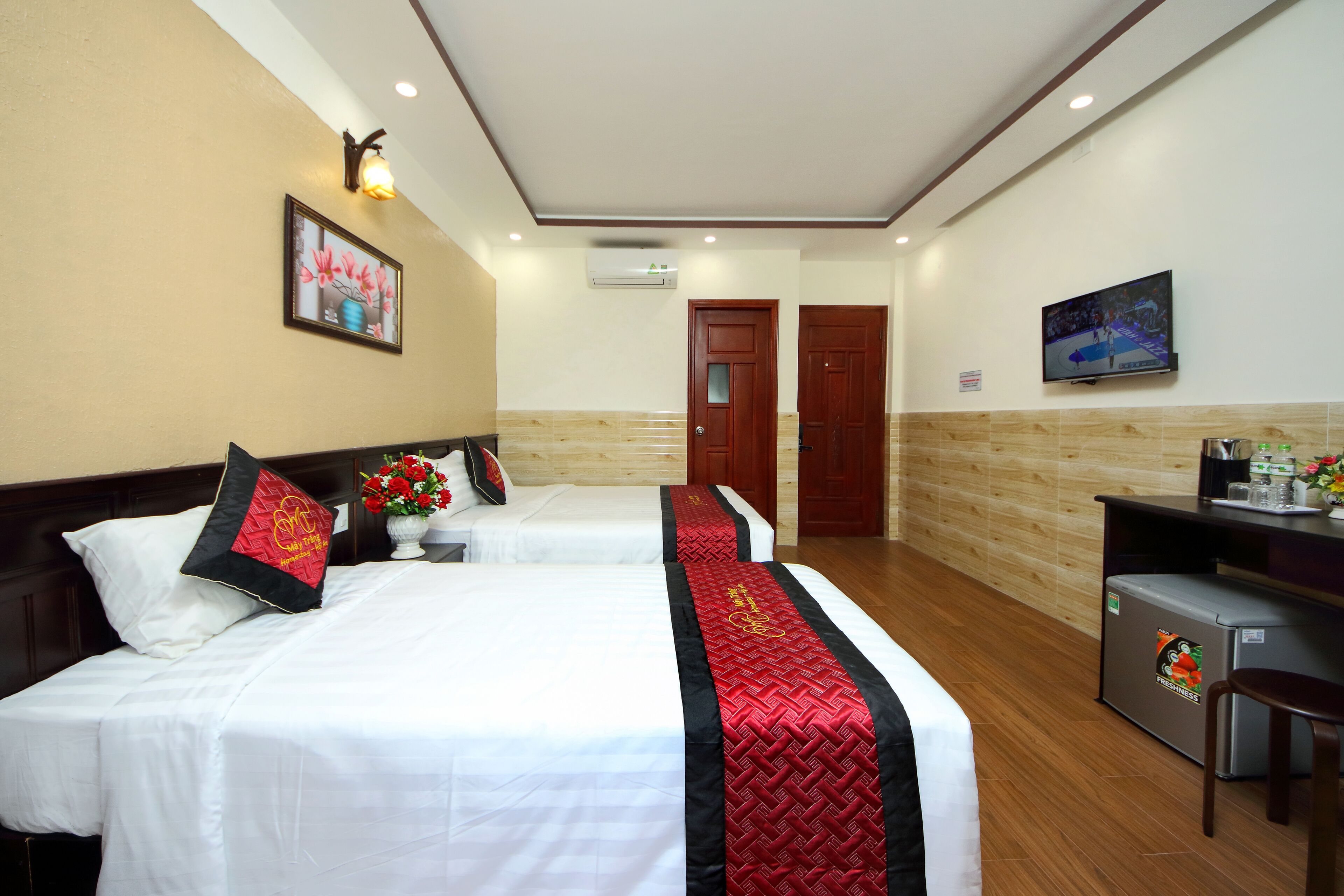 Habitación de hotel con dos camas, televisor, escritorio y refrigerador.